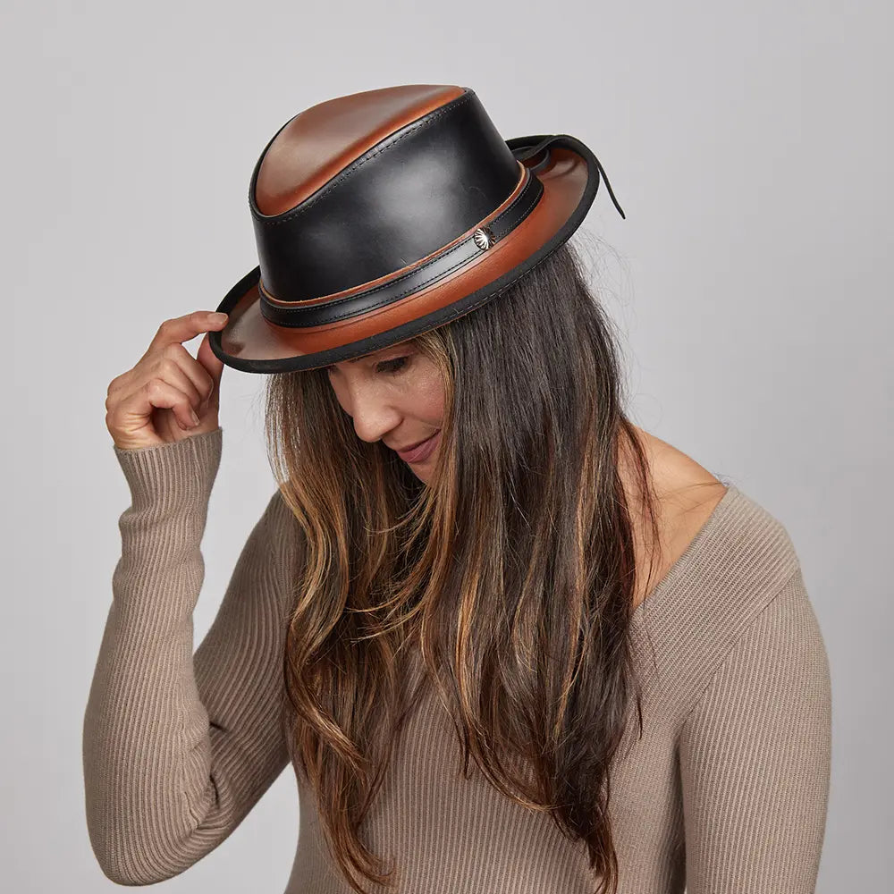 A woman in a long sleeve holding the tip of her black leather fedora