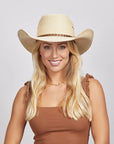 A smiling young woman with blonde hair wearing a Roper Cowboy Hat and a brown sleeveless top. 