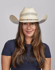 Woman with long brown hair wearing a Roughstock Cowboy Hat and a navy blue top