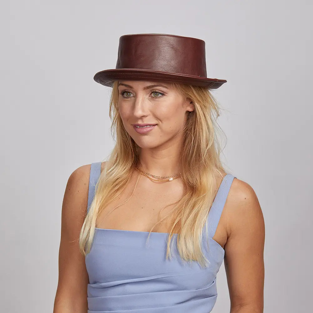A woman wearing a Brown Rumble Leather Hat and a blue sleeveless top.