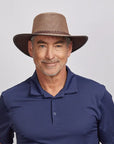 Middle-aged man with a friendly smile, wearing a brown mesh hat and a dark blue polo shirt
