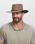 Man wearing a brown mesh fedora and a light beige polo shirt.