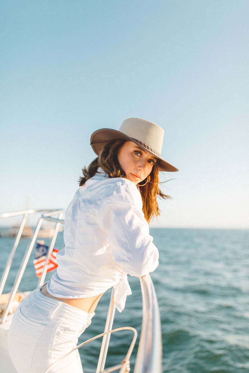 A woman with an ocean view wearing an eggshell sunhat