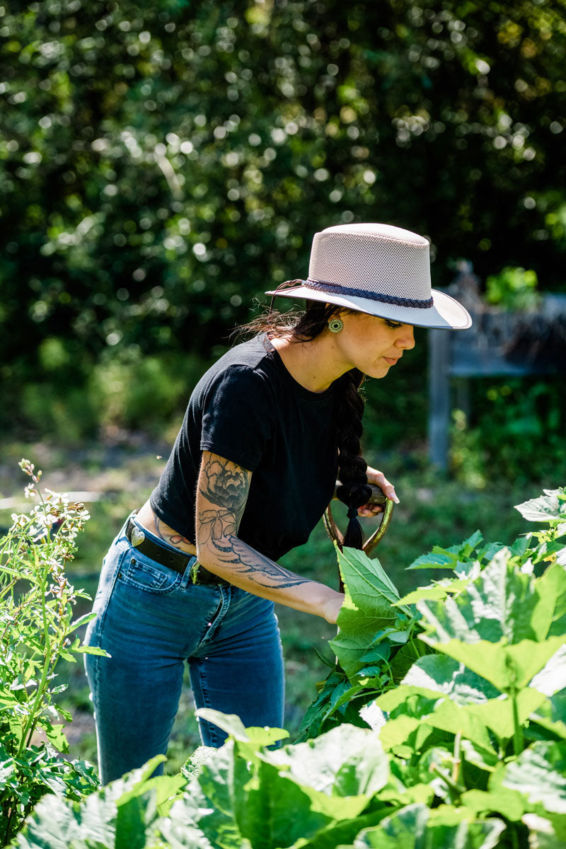 A woman wearing black shirt wearing a eggshell sun hat