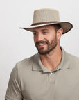 Man wearing a beige mesh fedora and a light beige polo shirt.