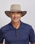 Middle-aged man with a friendly smile, wearing a beige mesh hat and a dark blue polo shirt