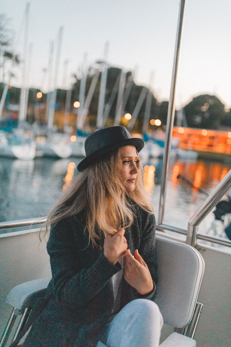 A woman in a boat wearing black leather hat