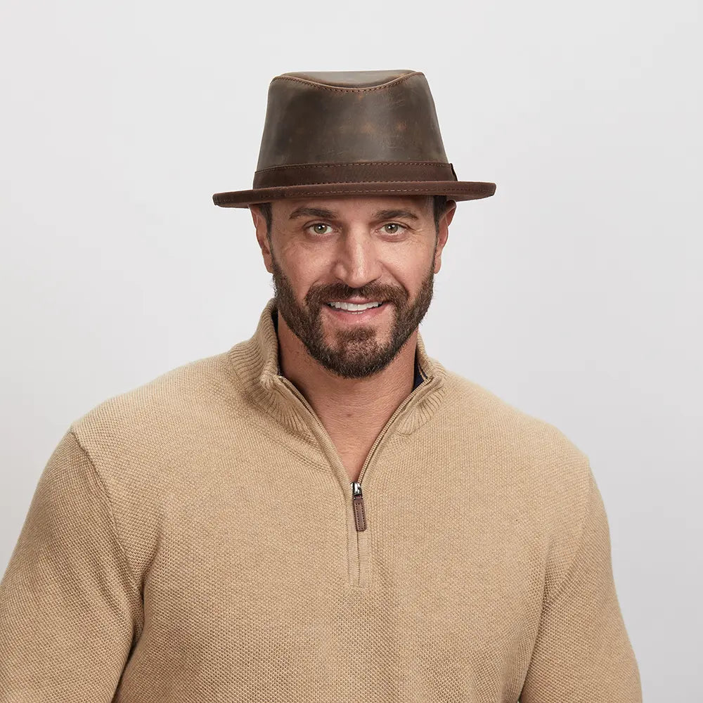 Man with a light stubble wearing a Soho Fedora Hat and beige zip-up sweater,