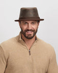 Man with a light stubble wearing a Soho Fedora Hat and beige zip-up sweater,