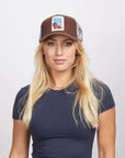 A blonde woman wearing a brown Spirit cap and a navy blue top.