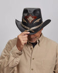 A man in a Beige shirt tipping his Black Storm Cowboy Hat.