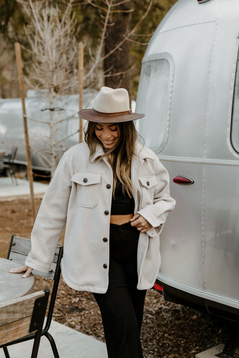 A woman standing outdoors wearing a felt leather fedora hat