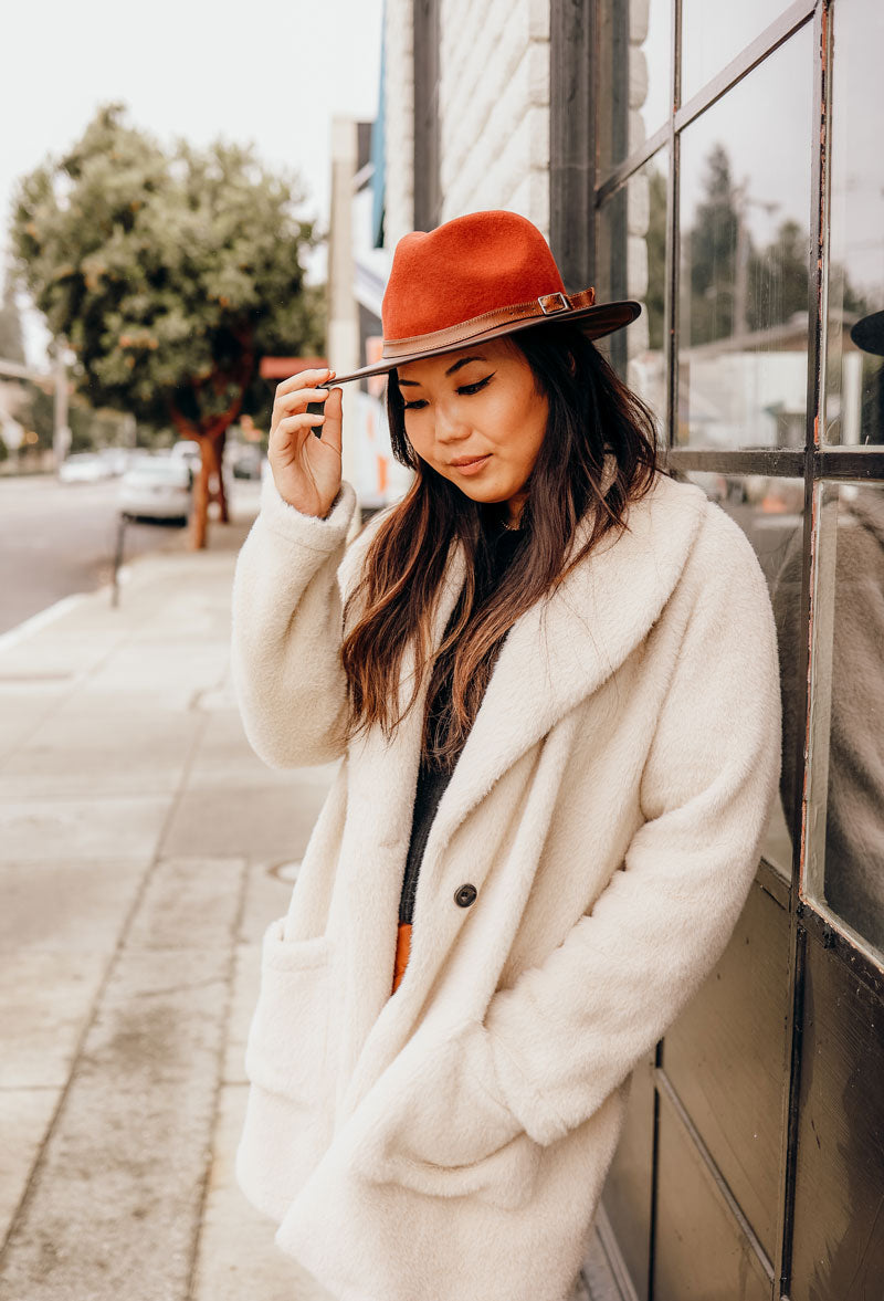 A woman on the walk way wearing a sangria felt leather hat