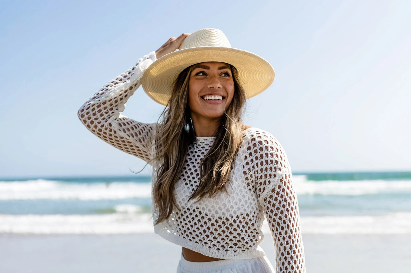 Woman at beach wearing the Taos straw womens sun hat by American Hat Makers
