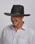 Man wearing a Titus Sun Hat and a light gray button-down shirt.