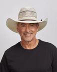 A smiling man wearing a black shirt and a straw cowboy hat