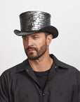 A man looking to the side wearing a black polo and a black top hat