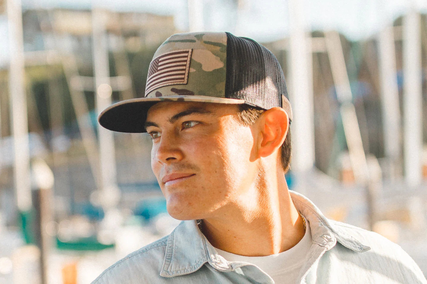 A smiling young man wearing a snapback cap by American Hat Makers