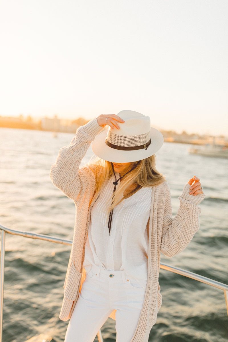A woman in a boat wearing tuscany cream sun hat
