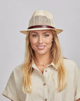 Smiling girl in a cream top and a straw sun hat