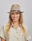 A happy woman wearing a cream top and the cream Tuscany straw sun hat
