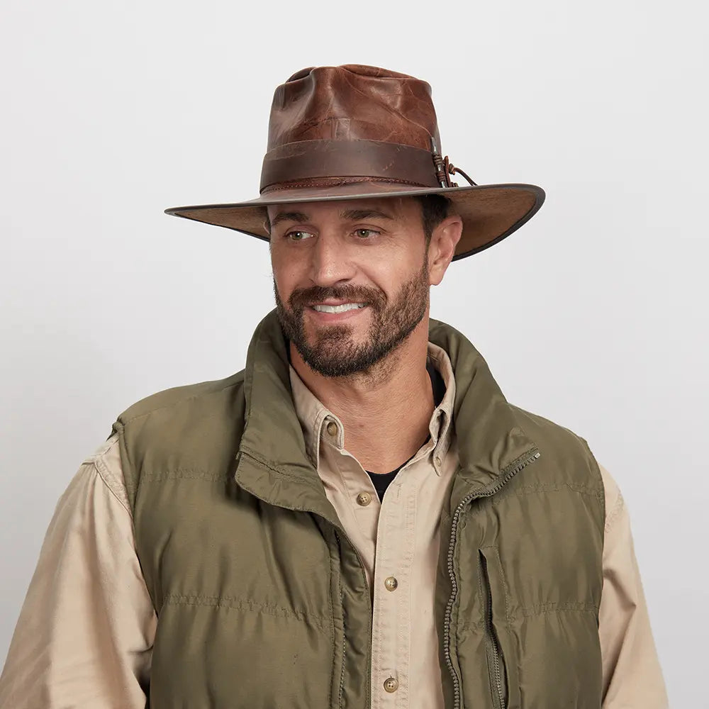 A smiling man looking to the side wearing a brown outback hat