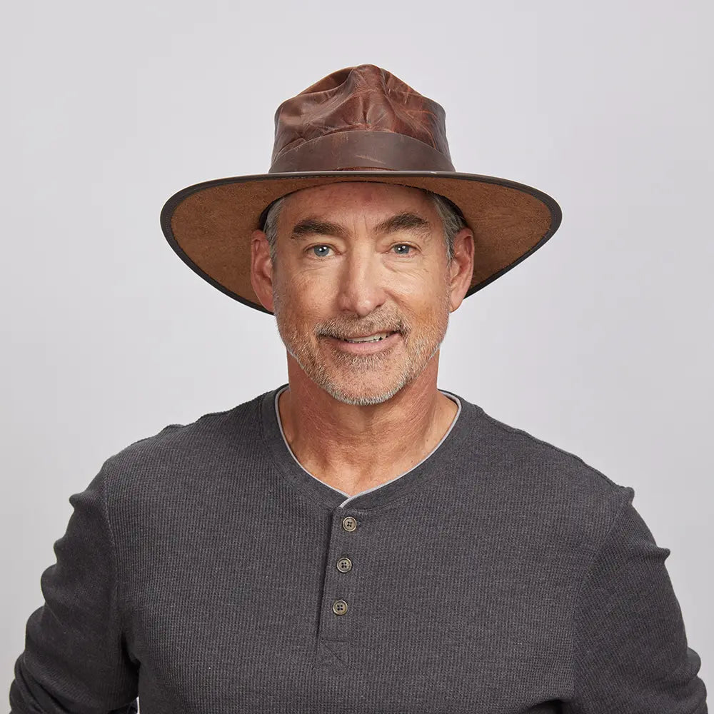 An old man wearing a grey top and a brown leather outback hat