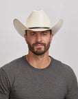 A young man in a grey shirt wearing an ivory cowboy hat