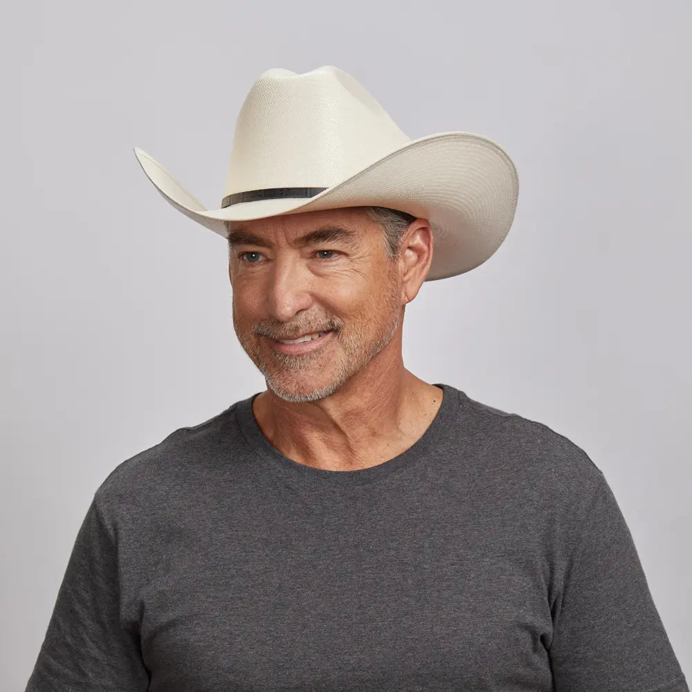 A man smiling and looking to the side wearing an ivory cowboy hat