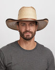 A man wearing a grey shirt and a natural straw cowboy hat