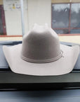 A white colored felt hat placed on a car's dashboard