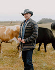 A man with cows behind him wearing Cyclone Black Leather Cowboy Hat with 3" Brim and 4" Crown