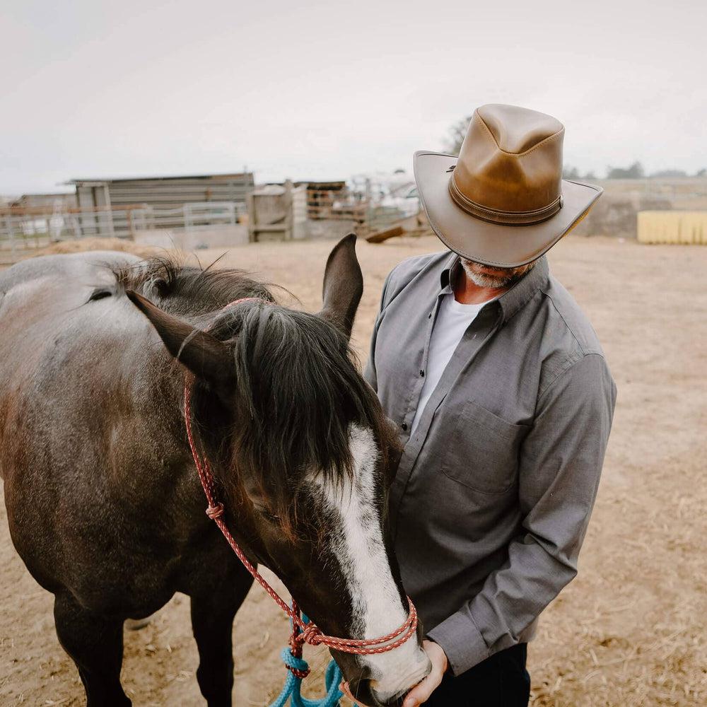 A man beside a horse wearing Burnt Honey Leather Cowboy Hat 