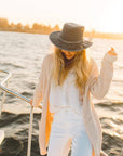 A woman enjoying her boat ride wearing knitted jacket and a hat