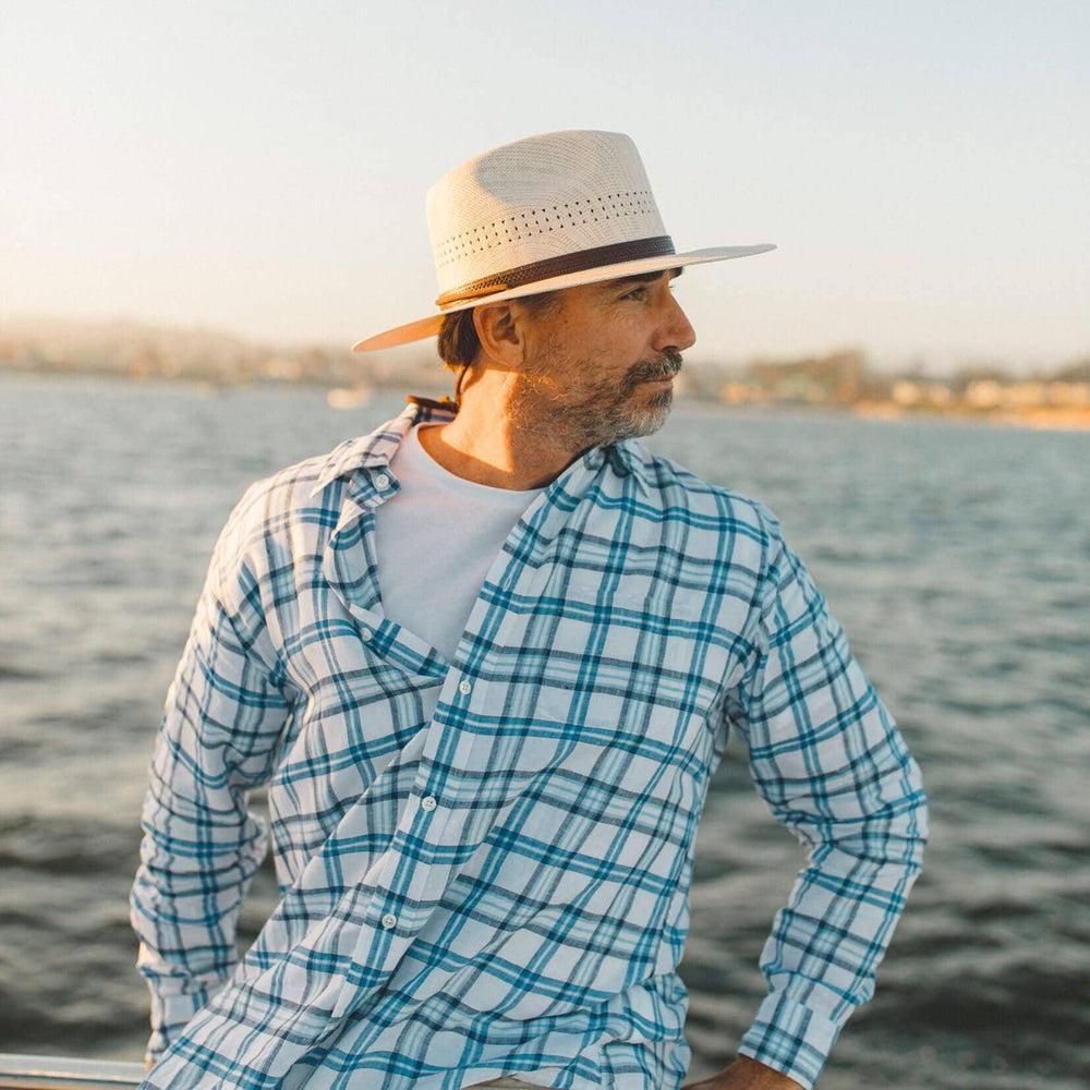 A man on the boat wearing checkered polo and a Straw Sun Hat