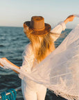 A woman in a boat wearing Copper Leather Mesh Sun Hat facing the ocean view