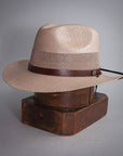 A side view of Milan Tan Straw Fedora Hat placed on a stand