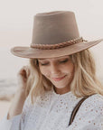 A woman on a beach wearing white blouse and a Copper Leather Mesh Sun Hat