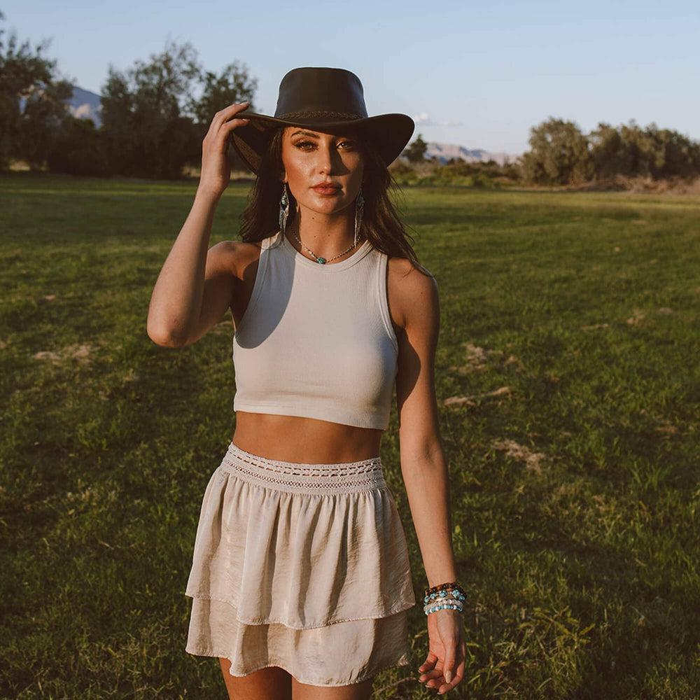 A woman standing in a yard wearing Leather Brown Bushman Outback Hat