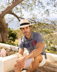 A man sitting on an overlooking view wearing  Panama Straw Fedora Hat