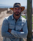 A man standing outdoor wearing Brown Outback Leather Hat