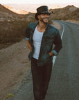 A man walking in the streets wearing El Dorado Black Leather Top Hat with a 5 Skull Band