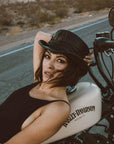 A woman on a motorcycle wearing Lil Evil Black Leather Top Hat