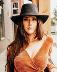 A woman wearing brown blouse and a Midnight Black Rider Leather Hat