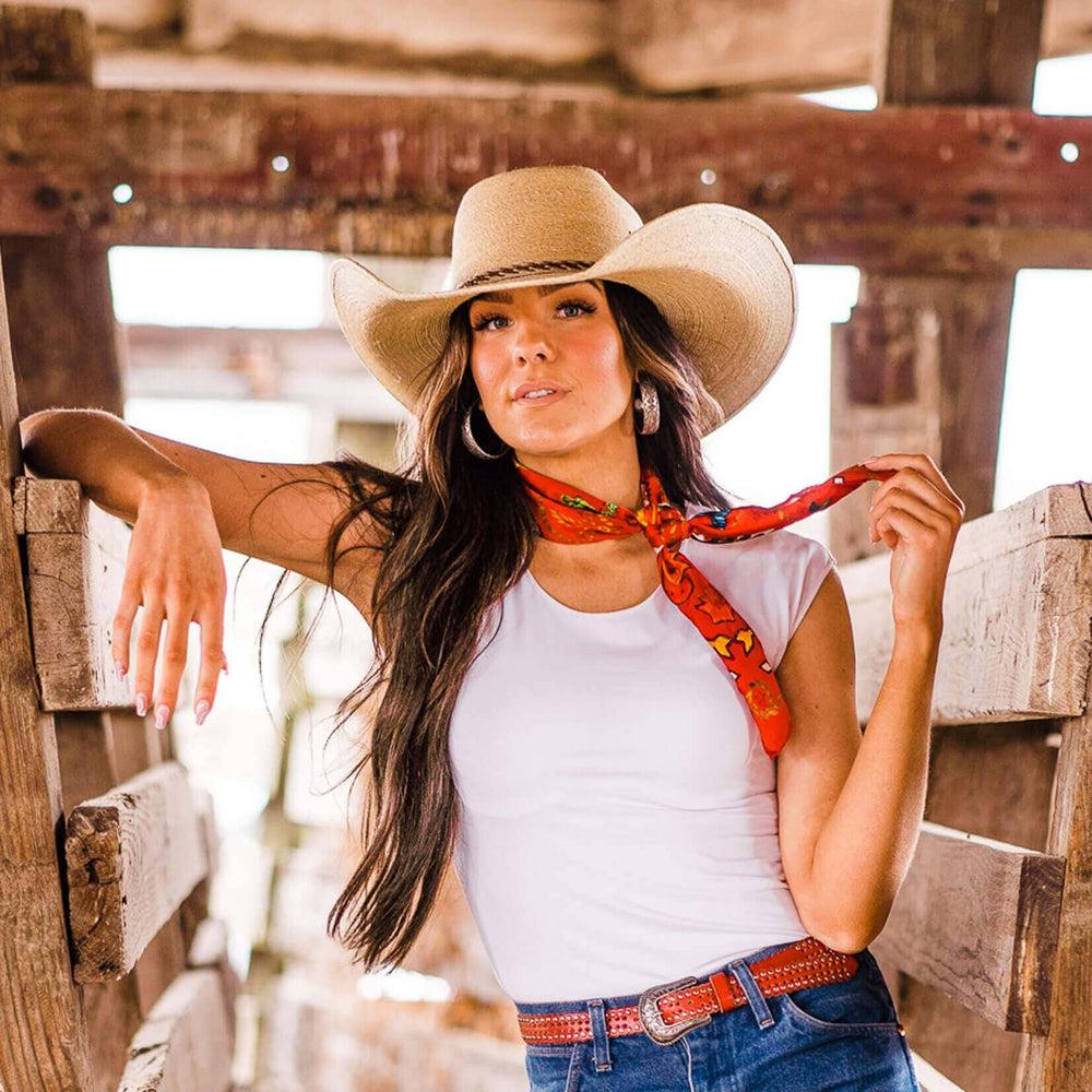 A woman in a white shirt leaning on a wooden fence wearing Roper Natural Palm Straw Hat