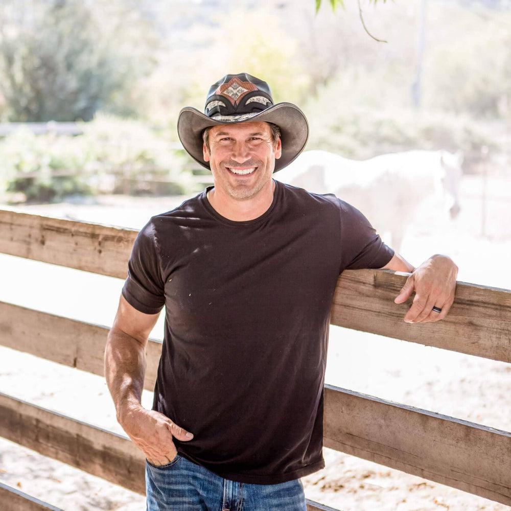 A man leaning in the fence wearing Black Finished Storm Cowboy Hat Double Rattle Band 