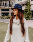 A woman standing outdoors wearing Summit Navy Leather Felt Fedora Hat 