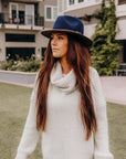A woman standing outdoors wearing Summit Navy Leather Felt Fedora Hat