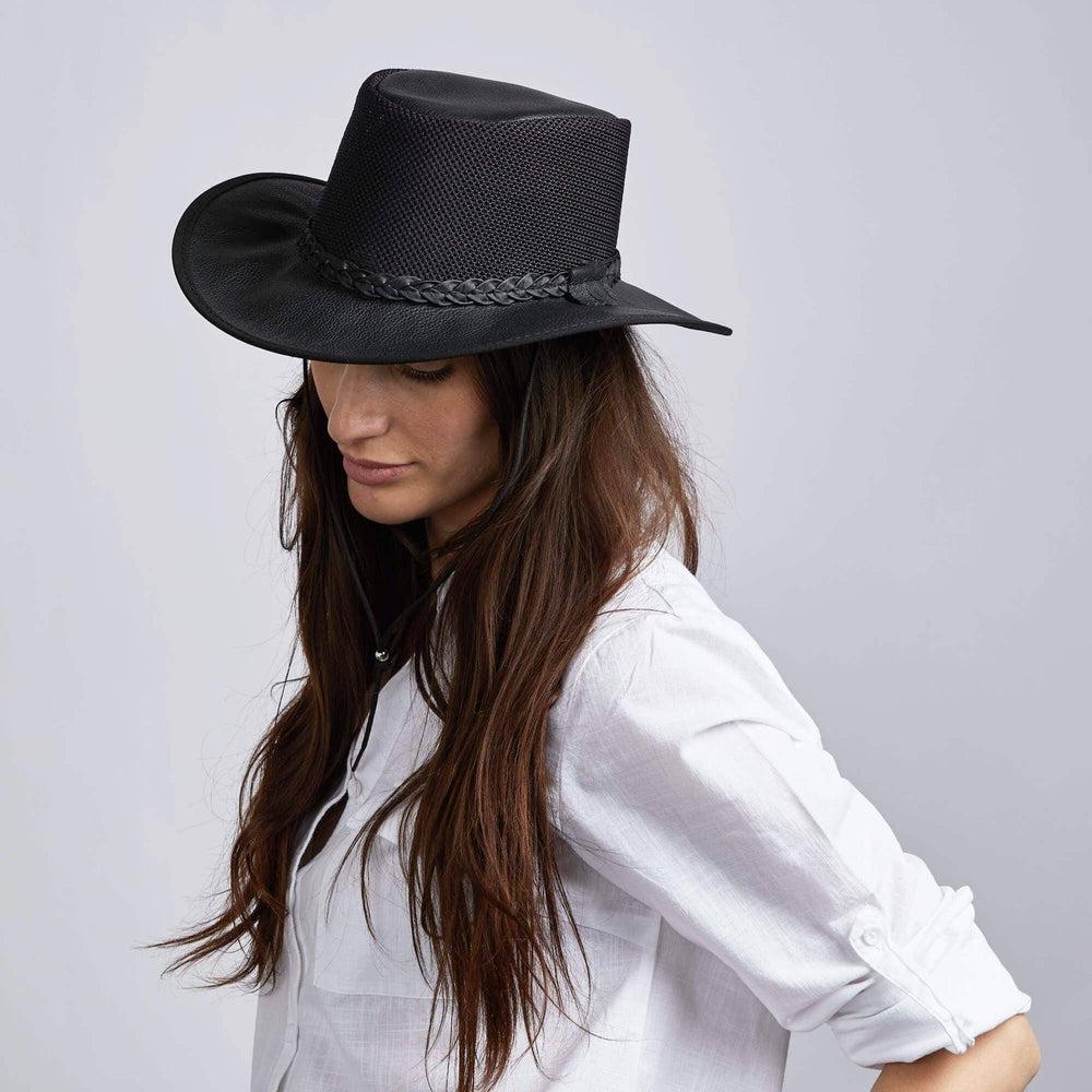 A woman facing side view and looking downwards wearing a black hat