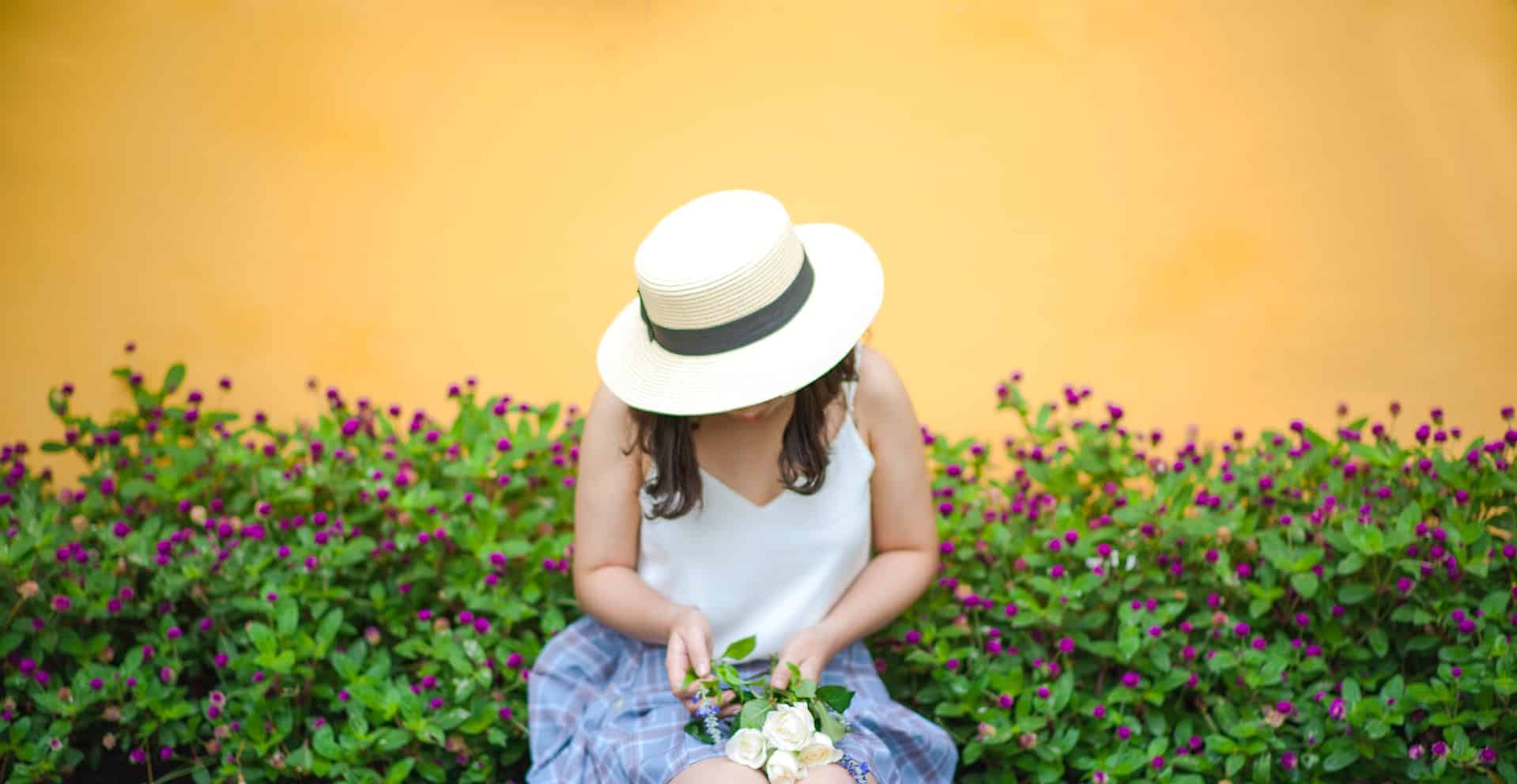 woman looking down with gardening hat on